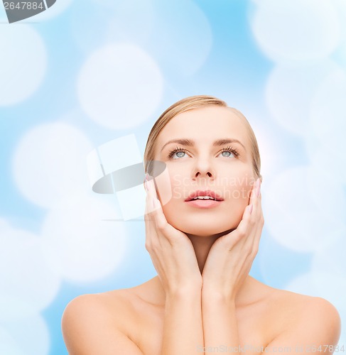 Image of beautiful woman touching her face and looking up