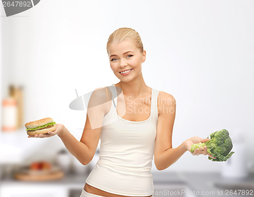 Image of smiling woman with broccoli and hamburger