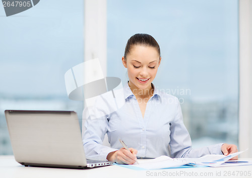 Image of businesswoman with laptop and charts in office