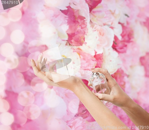 Image of woman hands spraying perfume