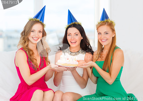 Image of three women wearing hats holding cake with candles