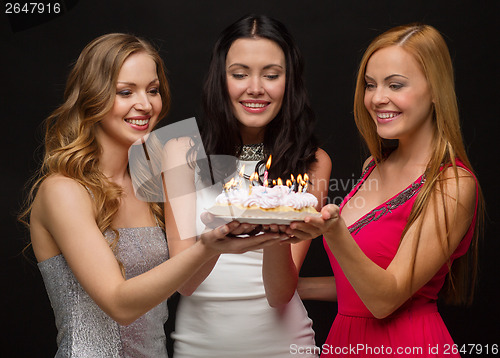 Image of three women holding cake with candles