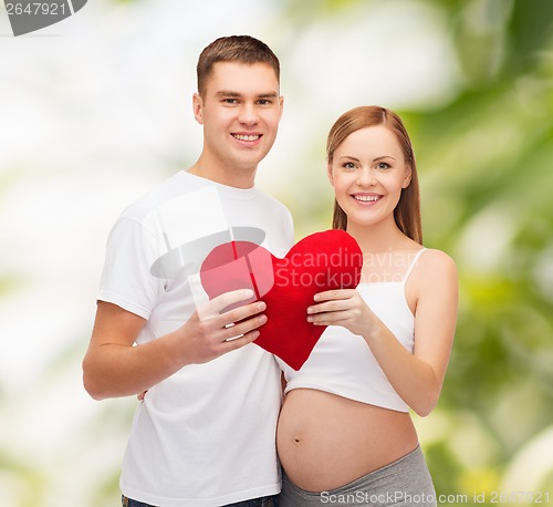 Image of happy young family expecting child with big heart