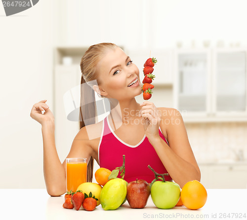 Image of smiling woman with organic food eating strawberry