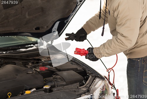 Image of closeup of man under bonnet with starter cables