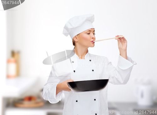 Image of smiling female chef with pan and spoon