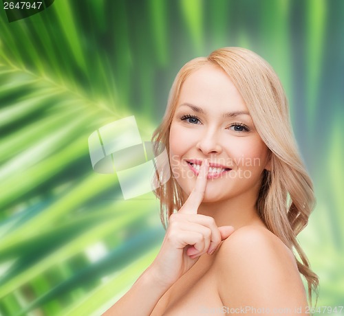 Image of beautiful young woman pointing finger to lips