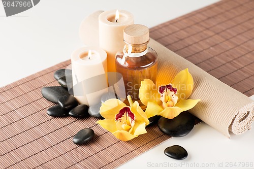 Image of essential oil, massage stones and orchid flower