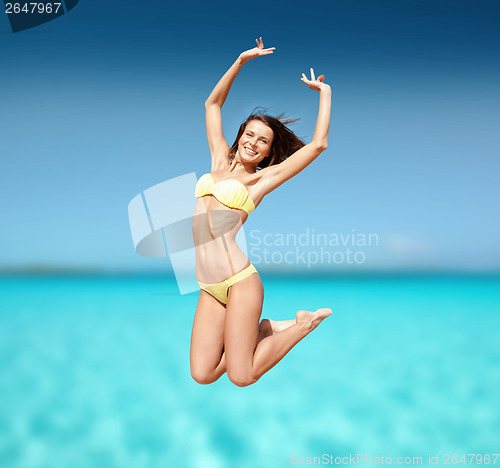 Image of woman in bikini jumping on the beach