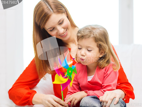 Image of happy mother and daughter with pinwheel toy