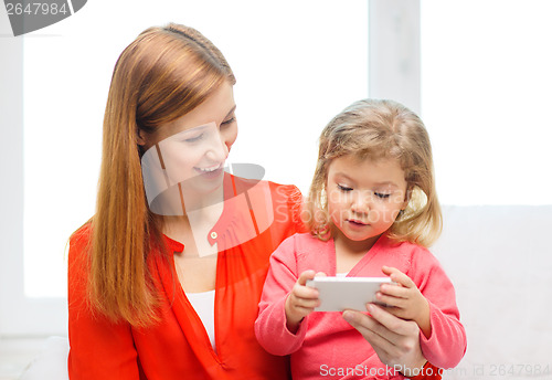 Image of happy mother and daughter with smartphone at home