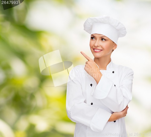 Image of smiling female chef pointing finger to sonething