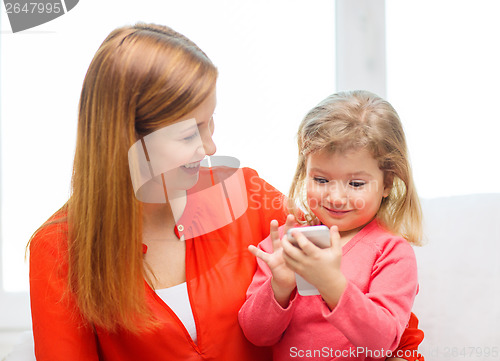 Image of happy mother and daughter with smartphone at home