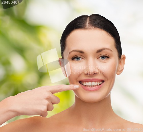 Image of young calm woman pointing to her mouth