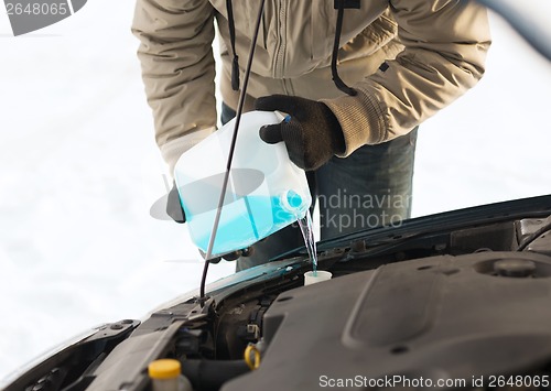 Image of closeup of man pouring antifreeze into water tank