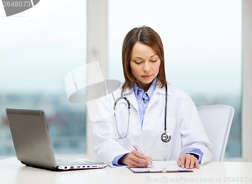 Image of busy doctor with laptop computer and clipboard