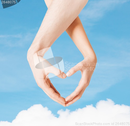 Image of woman and man hands showing heart shape