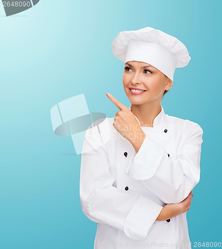 Image of smiling female chef pointing finger to sonething