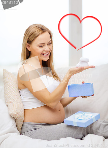 Image of smiling pregnant woman with gift box and bootees