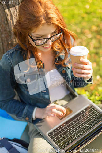 Image of teenager in eyeglasses with laptop and coffee