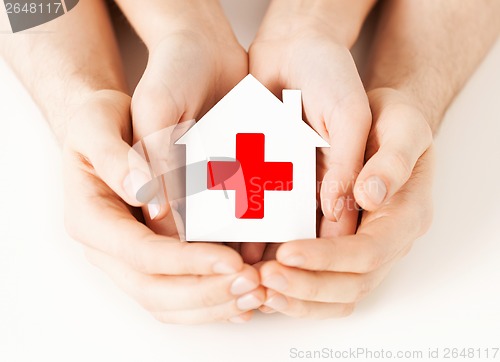 Image of hands holding paper house with red cross