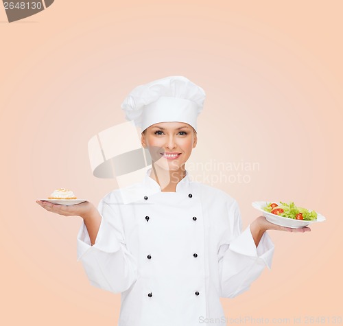 Image of smiling female chef with salad and cake on plates