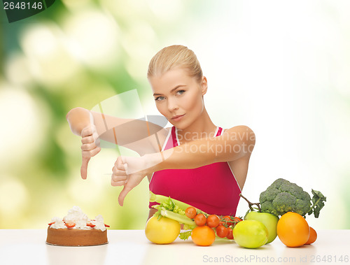 Image of woman with fruits showing thumbs down to cake