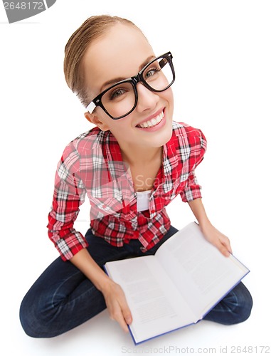 Image of smiling teenage girl in eyeglasses reading book