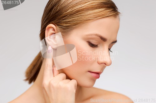 Image of calm woman touching her ear