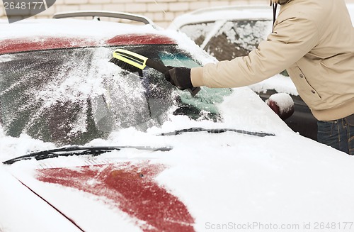 Image of closeup of man cleaning snow from car