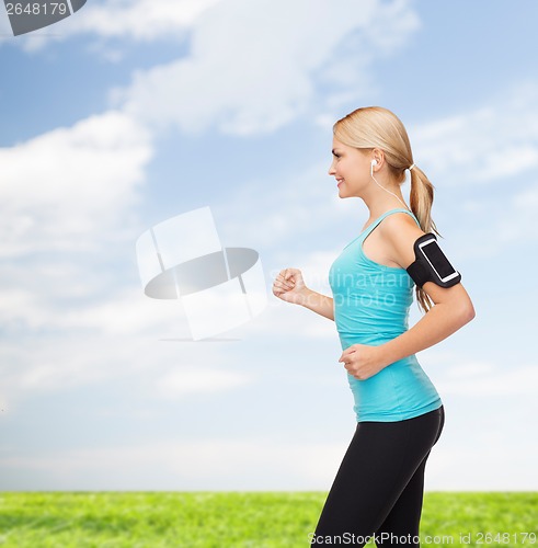 Image of sporty woman running with smartphone and earphones
