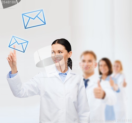 Image of smiling female doctor pointing to envelope