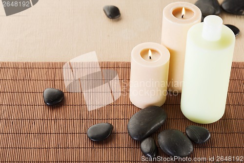 Image of shampoo bottle, massage stones and candles