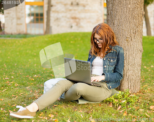 Image of smiling teenager in eyeglasses with laptop