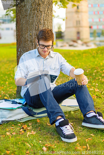 Image of teenager reading book with take away coffee