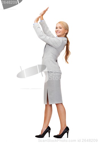 Image of businesswoman pushing up something imaginary