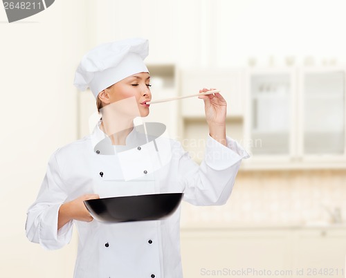 Image of smiling female chef with pan and spoon