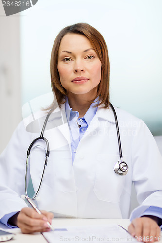 Image of busy doctor with laptop computer and clipboard
