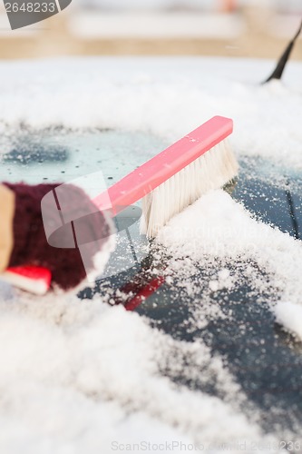 Image of woman cleaning snow from car back window