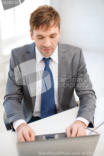 Image of businessman with laptop computer and documents