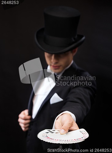 Image of magician in hat showing trick with playing cards