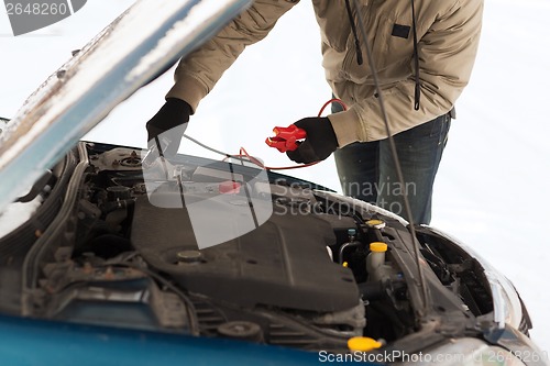 Image of closeup of man under bonnet with starter cables