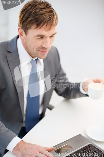 Image of smiling businessman working with laptop computer