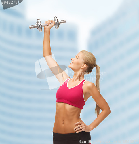 Image of smiling woman lifting steel dumbbell