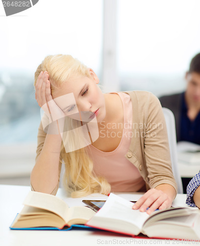 Image of tired teenage student with tablet pc and books