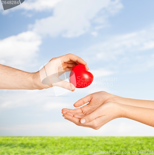 Image of man hand giving red heart to woman