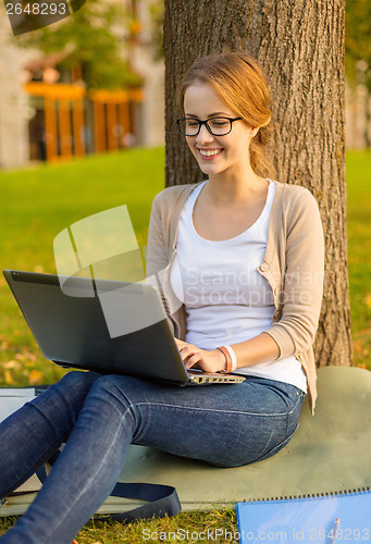 Image of smiling teenager in eyeglasses with laptop