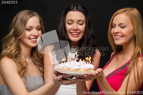 Image of three women holding cake with candles