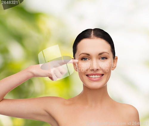 Image of young calm woman pointing to her eye