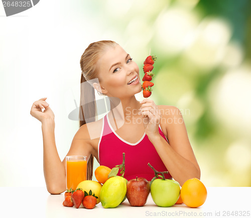 Image of smiling woman with organic food eating strawberry